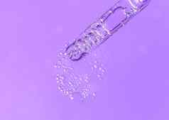 吸管流体透明质酸酸血清单色紫罗兰色的背景化妆品医疗保健概念特写镜头