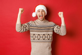 图像快乐的英俊的男人。宣誓者圣诞老人他庆祝一年并赢得提高手大喊大叫快乐站红色的背景