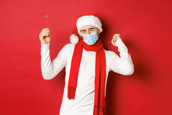 概念科维德圣诞节假期流感大流行快乐男人。庆祝一年聚会，派对穿医疗面具圣诞老人他跳舞炯炯有神的眼睛红色的背景
