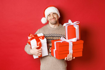 概念冬天假期一年庆祝活动肖像可爱的微笑男人。接收桩礼物持有礼物感动了惊喜站红色的背景感激的