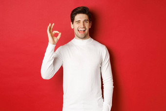 概念冬天假期圣诞节生活方式英俊的男人。白色毛衣眨眼显示标志微笑保证质量推荐