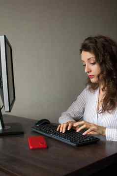 年轻的女办公室经理白色衬衫卷曲的头发坐着表格打字键盘例程工作自由