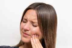 年轻的女人触碰脸颊强大的牙疼痛