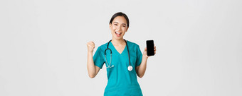 科维德医疗保健工人在线医学概念成功的快乐的亚洲女医生护士实习医生风云拳头泵喜乐显示智能手机屏幕应用程序很高兴相机