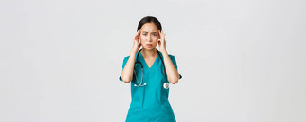 科维德医疗保健工人流感大流行概念过度劳累疲惫亚洲女医生医生感觉生病的穿实习医生风云触碰头抱怨头疼高发热