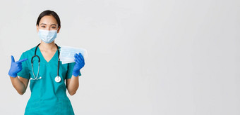科维德冠状病毒疾病医疗保健工人概念微笑亚洲女医生医生护士橡胶手套实习医生风云指出手指医疗面具病人安全