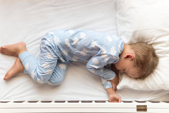 前视图可爱的年学前教育婴儿男孩孩子睡觉甜美白色婴儿床午餐休息时间蓝色的睡衣枕头首页童年休闲安慰医学健康概念