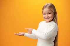孩子女孩指出手指复制空间黄色的背景