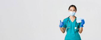 科维德冠状病毒疾病医疗保健工人概念微笑亚洲女医生医生护士橡胶手套实习医生风云指出手指医疗面具病人安全