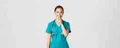 科维德医疗保健工人流感大流行概念快乐的微笑女亚洲护士实习医生风云秘密使惊喜显示嘘手势嘘安静的站白色背景