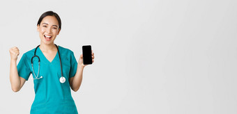 科维德医疗保健工人在线医学概念成功的快乐的亚洲女医生护士实习医生风云拳头泵喜乐显示智能手机屏幕应用程序很高兴相机