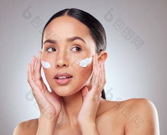 敏感的皮肤选择保湿霜舒缓的成分工作室拍摄美丽的年轻的女人应用保湿霜脸灰色背景