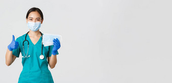 科维德冠状病毒疾病医疗保健工人概念微笑亚洲医生护士实习医生风云橡胶手套显示竖起大拇指医疗面具白色背景