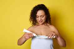 年轻的女人包装白色毛巾挤压牙膏电牙刷