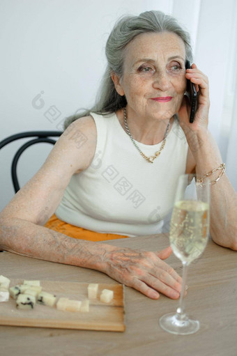 美丽的祖母灰色头发脸皱纹智能手机会说话的坐着表格首页窗口背景母亲的一天快乐退休