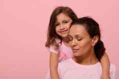 美丽的婴儿女孩粉红色的衣服粉红色的丝带温柔拥抱妈妈。关闭眼睛相机显示支持癌症病人幸存者粉红色的背景复制空间