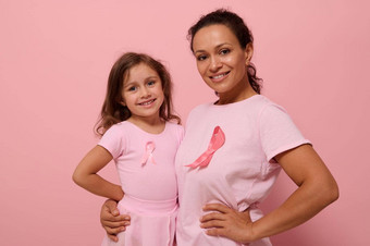 孤立的肖像彩色的背景复制空间混合比赛女人拥抱可爱的婴儿女孩穿粉红色的衣服<strong>乳房癌症意识</strong>丝带显示团结<strong>癌症</strong>幸存者