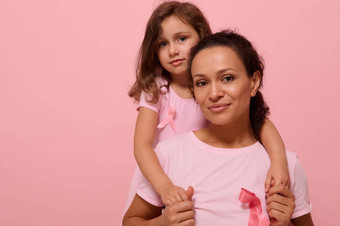 宁静女人女孩粉红色的服装<strong>乳房癌症意识</strong>丝带女儿拥抱妈妈。持有手相机支持<strong>癌症</strong>病人粉红色的背景复制空间