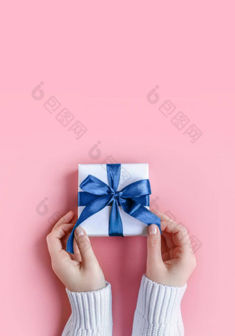 女手持有礼物白色包装纸粉红色的背景