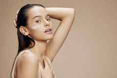 美丽的女人脸面具奶油清洁皮肤面部擦洗米色背景
