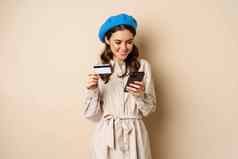肖像美丽的年轻的女人年移动电话购物应用程序信贷卡订单交付购买站米色背景