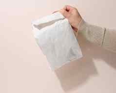 女手持有完整的纸袋米色背景拒绝塑料包装食物交付