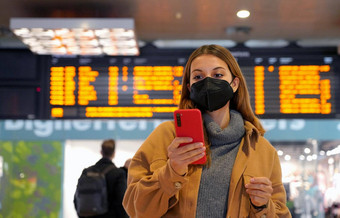 旅行者女人穿断续器脸面具地铁站年轻的女人时间表离职移民检查信息移动电话内部火车站
