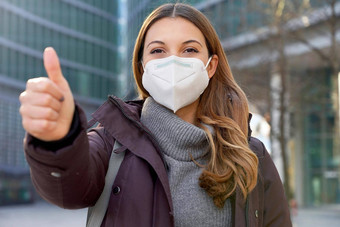 关闭乐观业务女人穿保护面具断续器显示拇指现代城市街相机