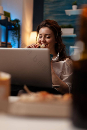 特写镜头肖像微笑女人看在线显示移动PC电脑美味的零食