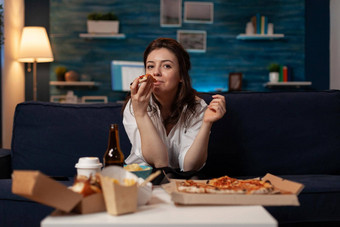女人办公室工作采取咬片热交付披萨看电视