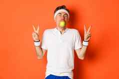 肖像有趣的中年运动员持有苹果口显示和平迹象站橙色背景锻炼统一的