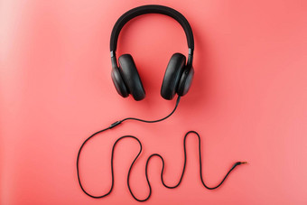 黑色的耳机粉红色的背景声音频率使耳机线入耳式耳机玩游戏听音乐跟踪