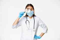 有趣的亚洲女人医生放大玻璃病人穿医疗脸面具橡胶手套白色背景
