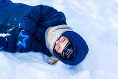 微笑快乐孩子谎言雪堆阳光明媚的冬天一天很多雪冷淡的活跃的冬天户外游戏