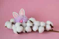 美丽的白色棉花花小毛茸茸的淡紫色玩具兔子粉红色的背景复活节概念