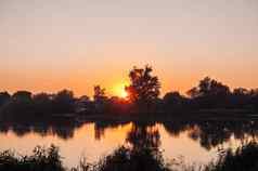 橙色日落背景河9月收获季节反射水树美丽的秋天景观秋天颜色反映了平静水域