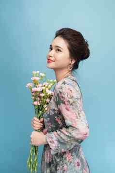 有吸引力的亚洲女人浪漫的衣服持有花束花蓝色的背景