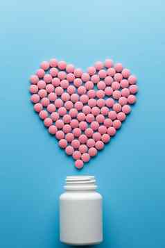 粉红色的药片形状心蓝色的背景倒白色