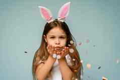 美丽的女孩兔子耳朵吹五彩纸屑相机复活节假期概念