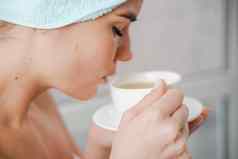 年轻的宁静放松女人水疗中心浴毛巾喝热饮料茶咖啡采取淋浴浴首页美治疗水合作用概念