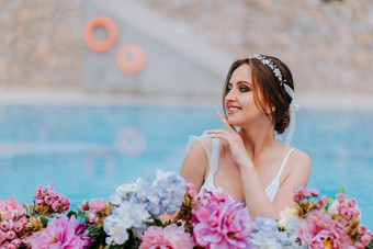 美丽的新娘美丽的白色泳衣花环花站游泳池花绿松石水美丽的女孩水池阳光明媚的一天