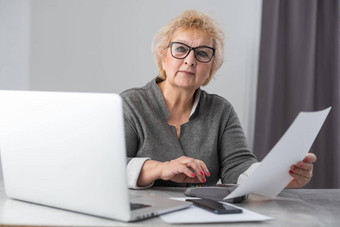 中间岁的老女人家庭主妇阅读纸信比尔坐着厨房首页办公室检查金融税费用回顾银行账户贷款利率信息医疗保险成本