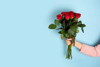 手持有美丽的大花束红色的玫瑰光蓝色的背景时尚的海报情人节一天国际女人的一天母亲一天横幅复制空间