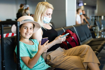 妈妈。女儿旅游穿保护卫生面具脸坐着<strong>机场</strong>终端的想法安全正常的旅行者社会距离