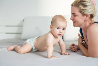 妈妈。孩子白色床上妈妈婴儿男孩尿布玩阳光明媚的卧室父孩子放松首页家庭有趣的床上用品纺织婴儿托儿所