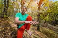 肖像成熟的男人。围巾头坐在拉紧的slackline解释了平衡秋天森林
