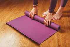 女孩了淡紫色瑜伽席锻炼实践首页木地板上