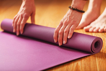 女人的手躺淡紫色瑜伽健身席锻炼实践首页木地板上