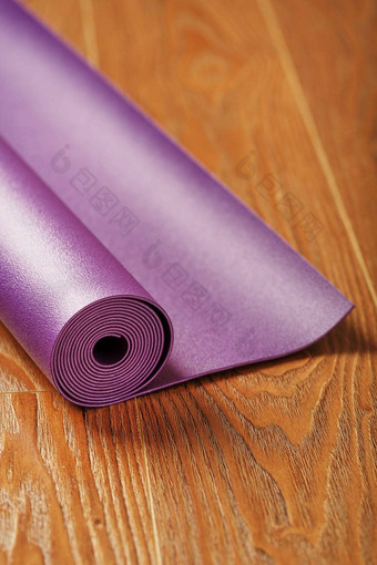 淡紫色瑜伽席扭曲的木地板上