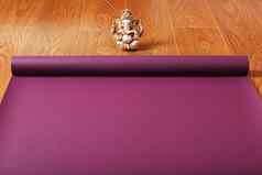 lilac-colored瑜伽席传播木地板上富拉蒂小雕像